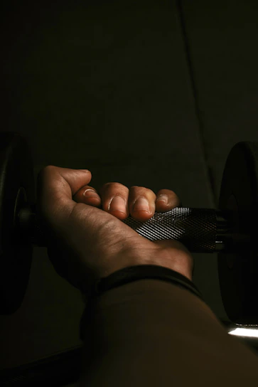 A powerful close-up of a muscular athlete gripping heavy lifting straps under dramatic gym lighting.