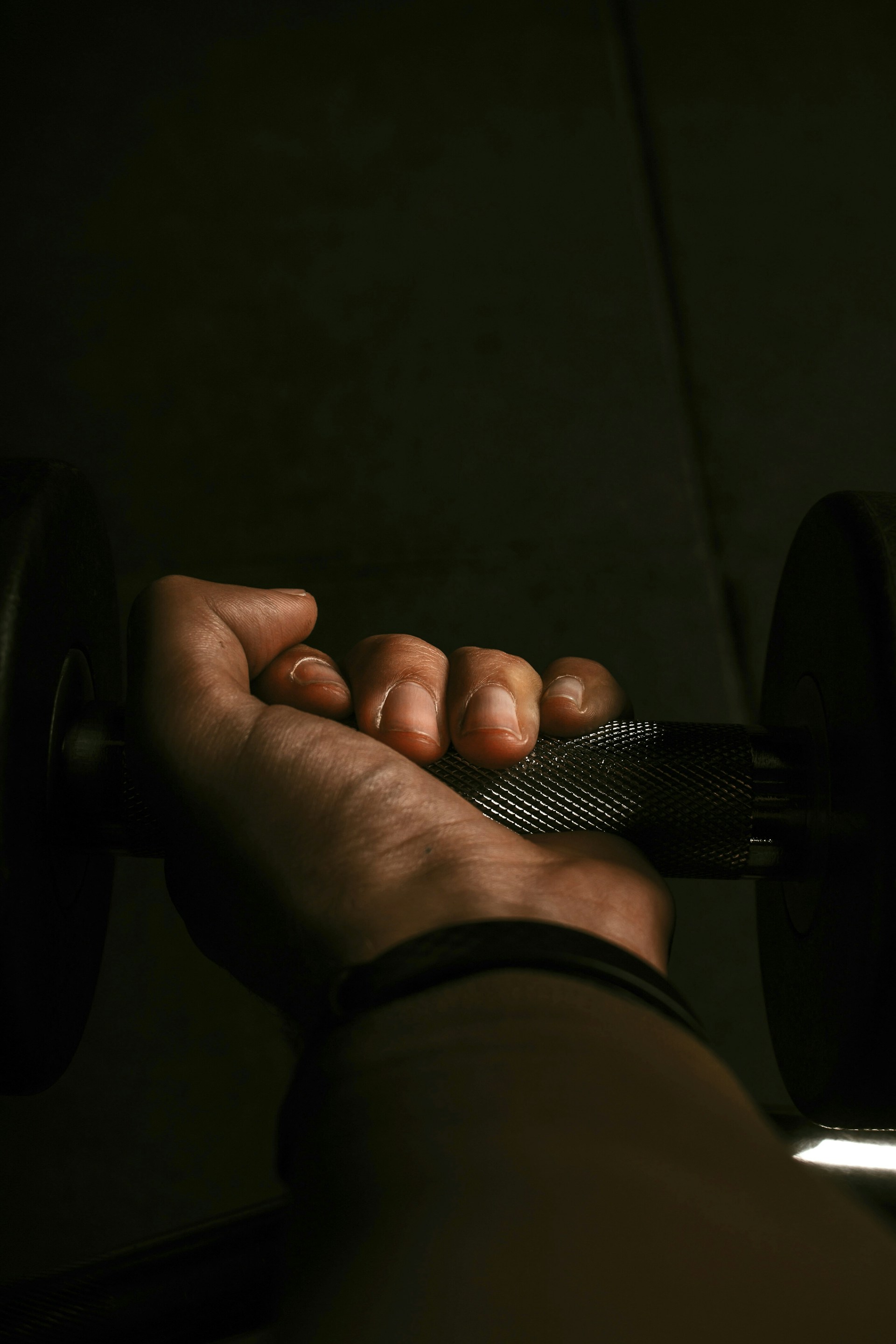 Close-up of hands gripping a barbell, chalk dust floating in the air against a sleek black background.