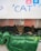 Three kittens are nestled together on a green blanket inside a small shelter. The setting appears cozy and secure, with a textured metallic background. A playful handwritten sign above features the word 'CAT' and some playful icons.