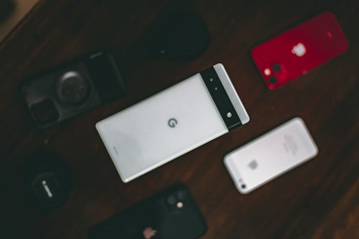 A collection of various smartphones is arranged on a dark surface. The central phone features a distinctive design with a horizontal black band at the top. Surrounding it are other phones, including a red-backed model and a silver-backed one. The layout suggests a comparison or display of different phone models.