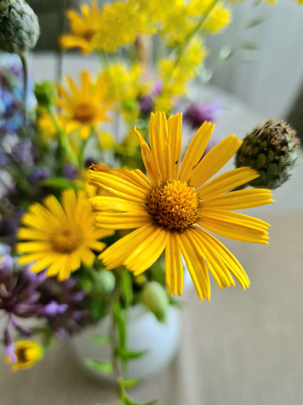 a vase filled with yellow and purple flowers