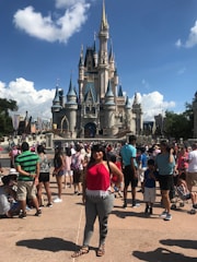 A group of excited teenagers posing in front of the iconic Disney castle, smiling and holding travel bags.