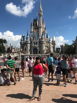 A group of excited teenagers posing in front of the iconic Disney castle, smiling and holding travel bags.