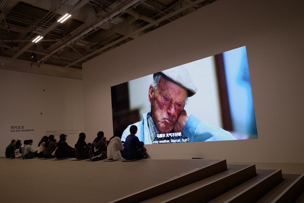 a group of people sitting in front of a large screen