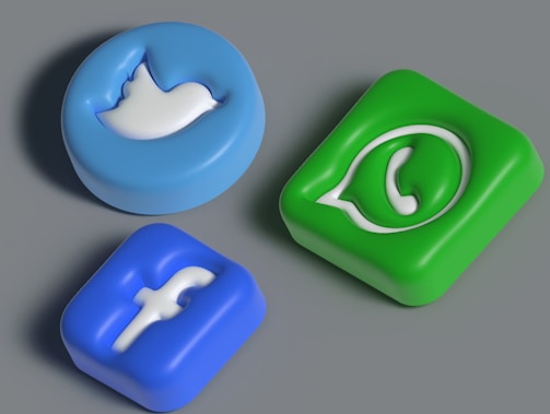 Three three-dimensional icons representing popular social media platforms are arranged against a neutral background. The icons have an embossed look, featuring a blue bird, a blue letter 'f', and a green phone symbol.