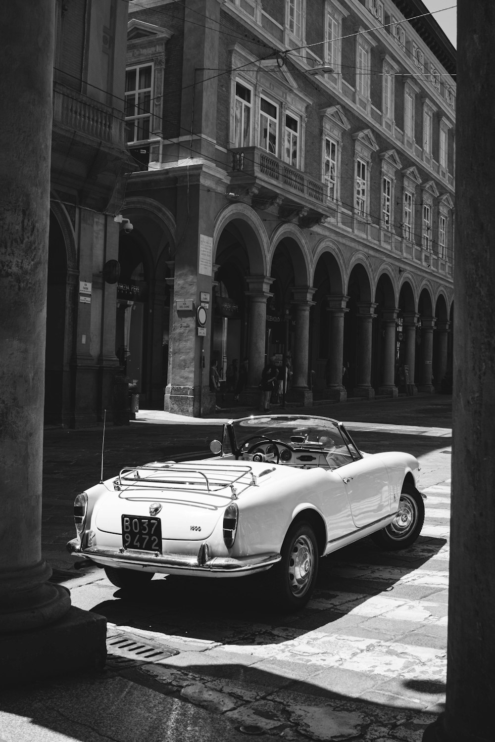 a white car parked in front of a tall building