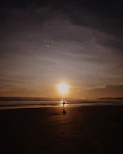 Early morning run along the beach with a coach encouraging a client under soft sunrise light.