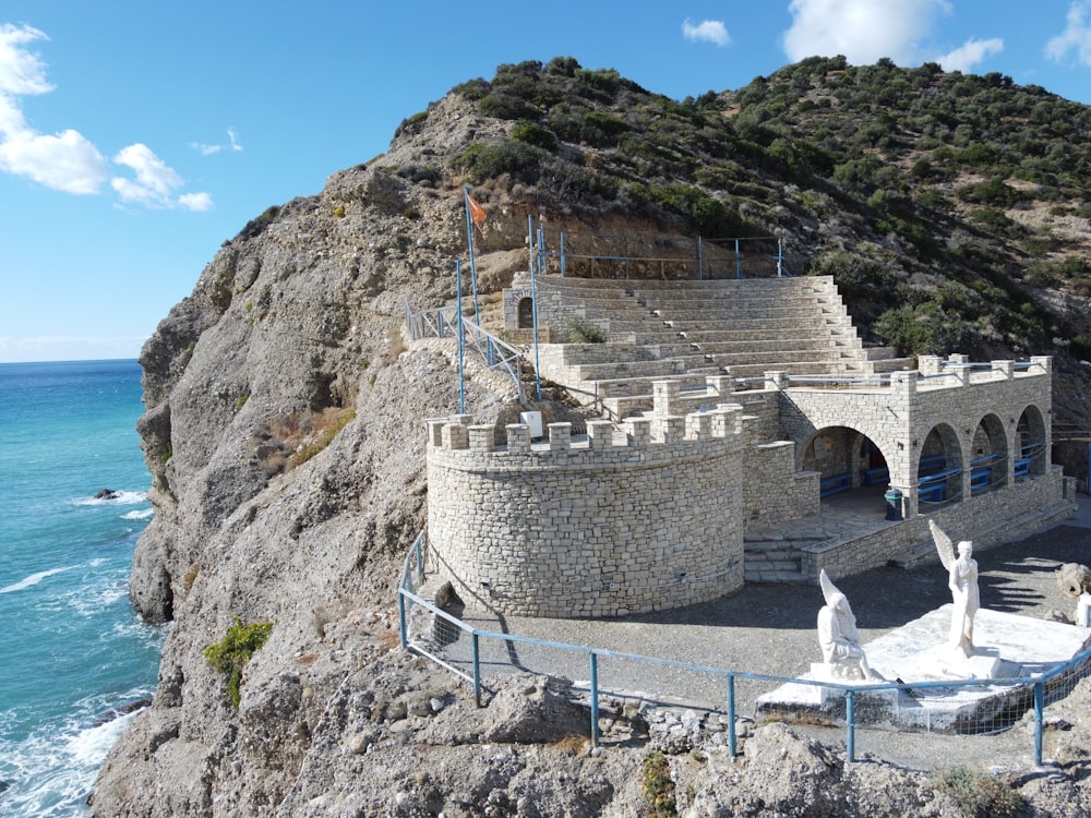 a large stone structure sitting on top of a cliff next to the ocean