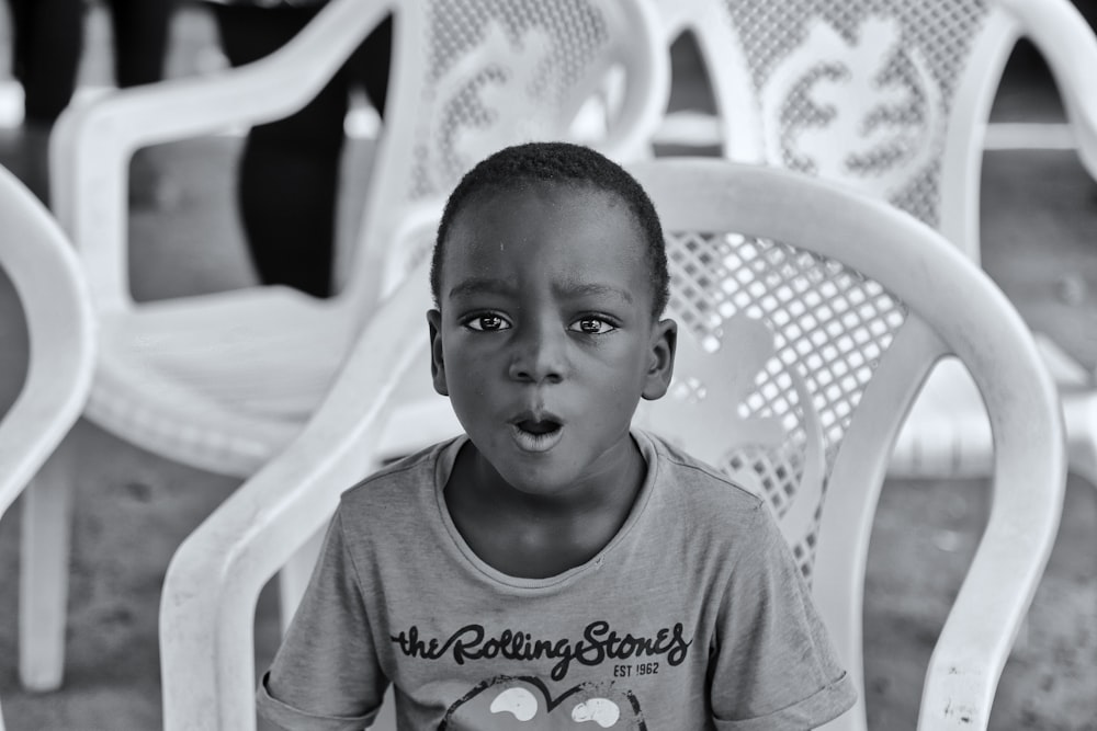 a young boy sitting in a chair making a funny face