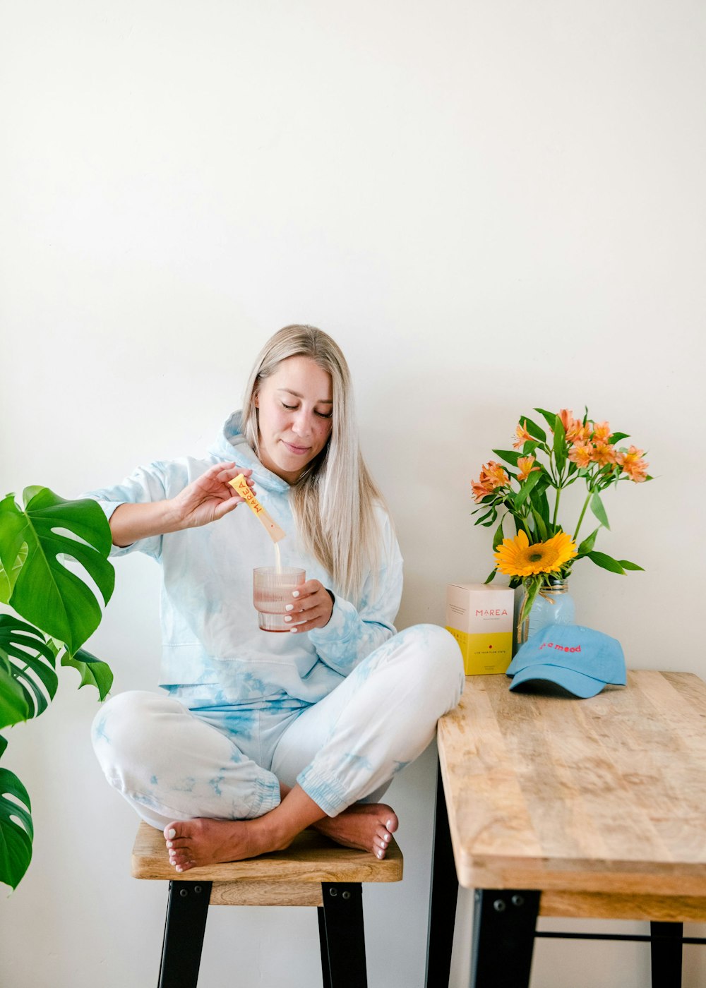 a woman sitting on a stool holding a drink