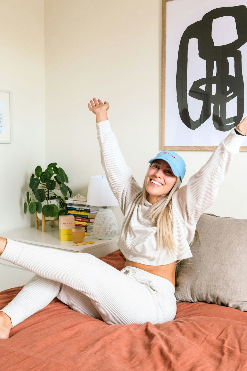 a woman sitting on a bed with her arms in the air