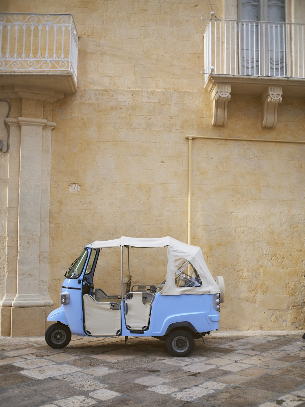 a small blue car parked in front of a building