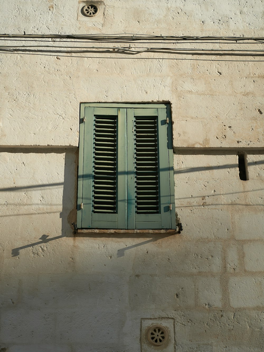 a window with green shutters on a white building