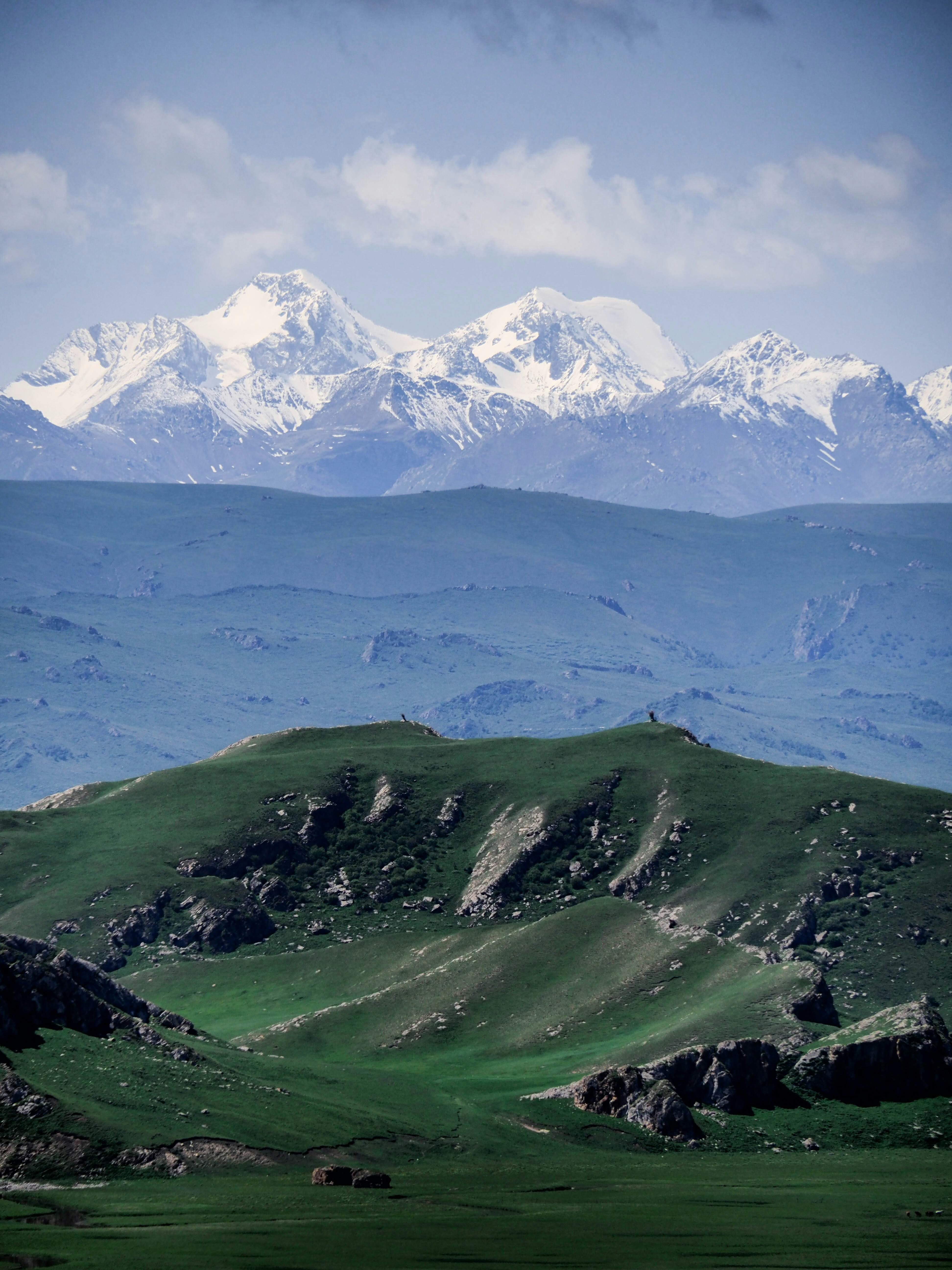 A mountain range with snow capped mountains in the distance photo ...