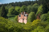 A magical castle surrounded by lush greenery and soft pastel skies.