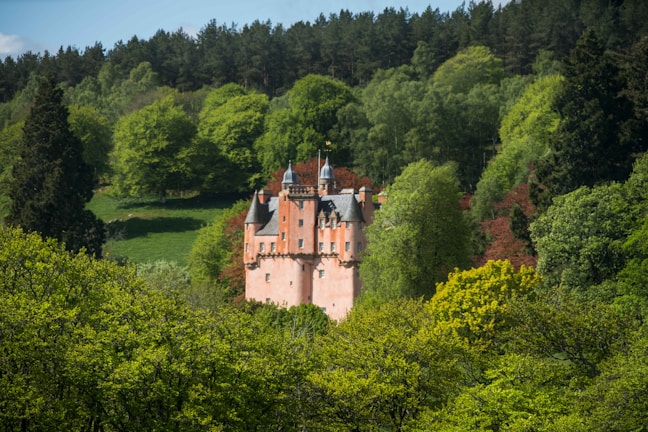 A magical castle surrounded by lush greenery and soft pastel skies.