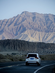 A happy traveler unlocking a sleek rental car with scenic mountains in the background.