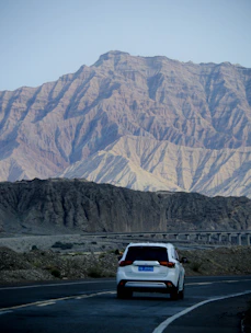 A happy traveler unlocking a sleek rental car with a scenic American highway in the background.