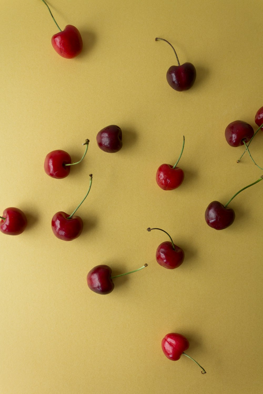 a group of cherries on a yellow surface