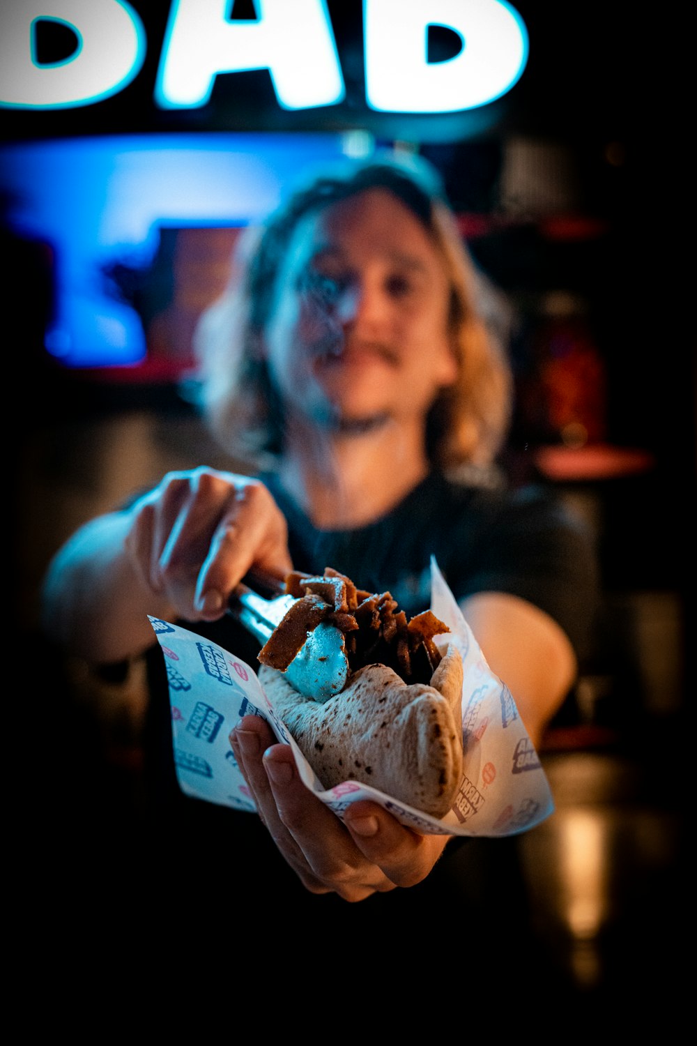 a woman holding a sandwich in front of a bar