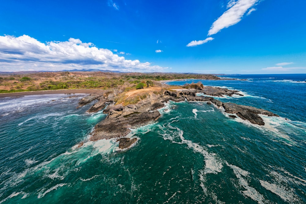 an aerial view of the ocean and a rocky shoreline