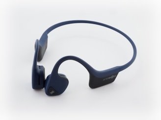 Wireless bone conduction headphones with a sleek, curved design and dark blue color. Features padded earpieces and a flexible band, suitable for sports or outdoor activities.