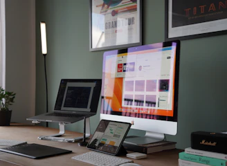 A friendly technician holding a MacBook, working in a bright, modern office filled with Apple devices.