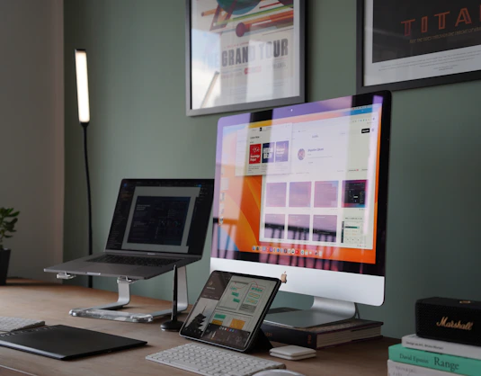 A friendly technician holding a MacBook, working in a bright, modern office filled with Apple devices.