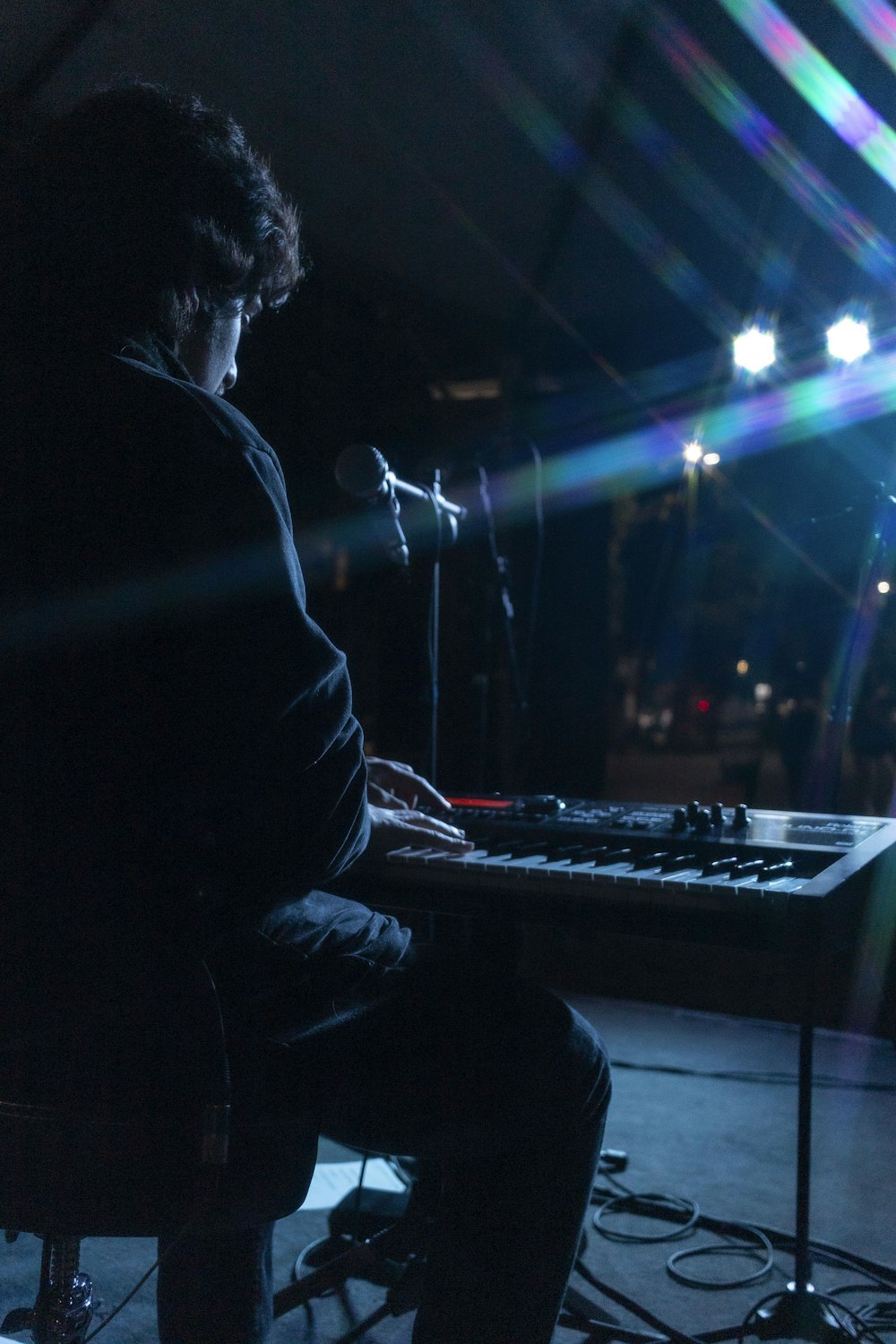 a man sitting at a keyboard in front of a microphone