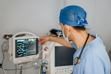 a man in scrubs and a stethoscope looking at a monitor