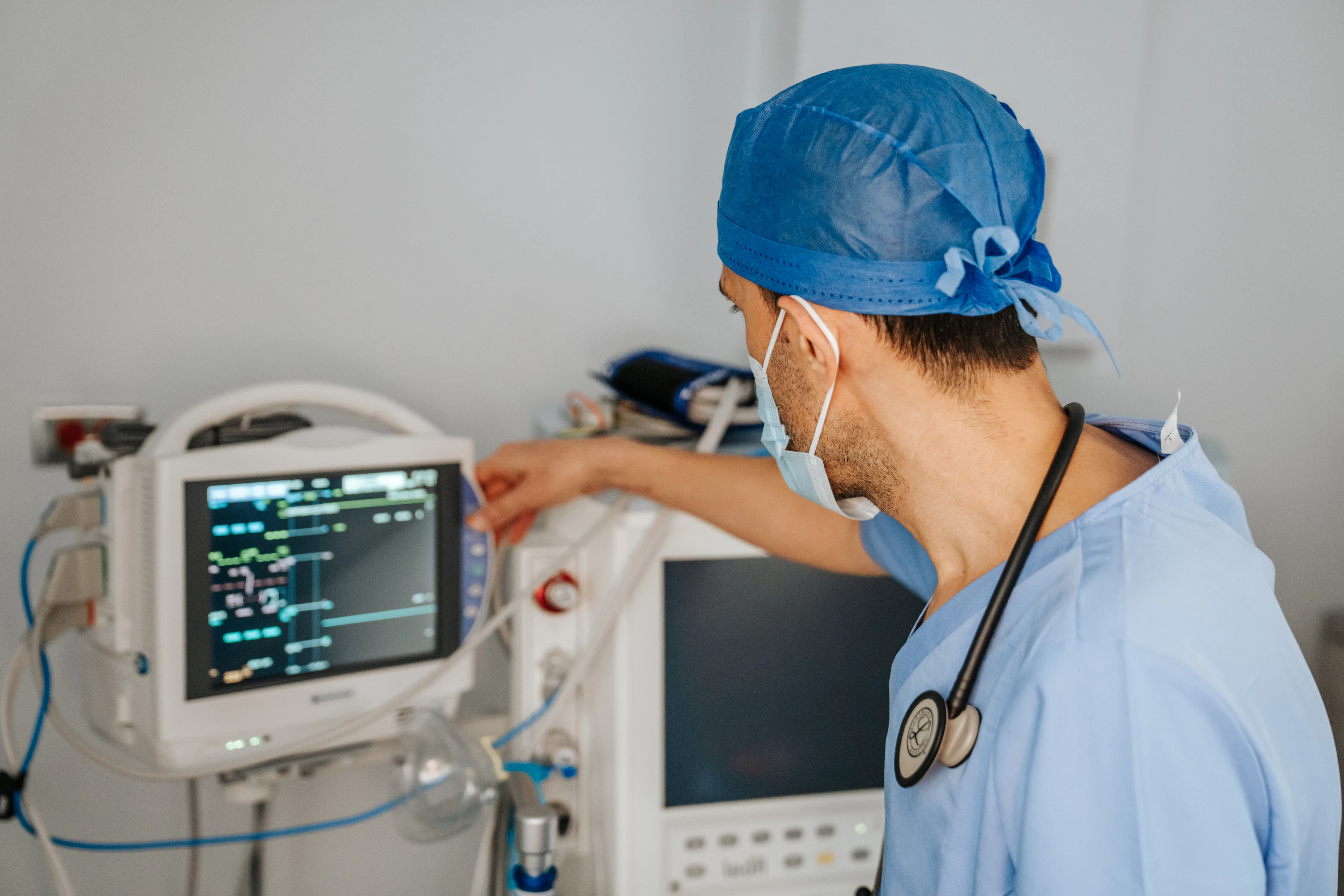 A clinician in scrubs reading a patient monitor