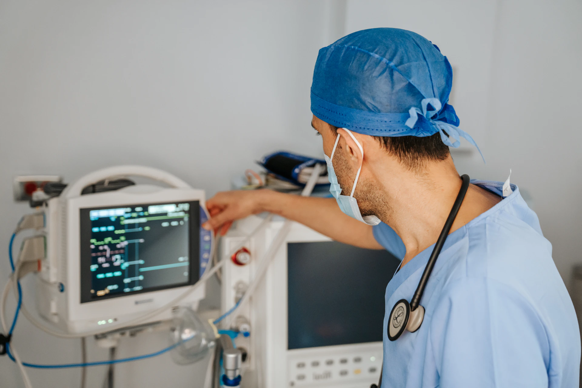 a man in scrubs and a stethoscope looking at a monitor