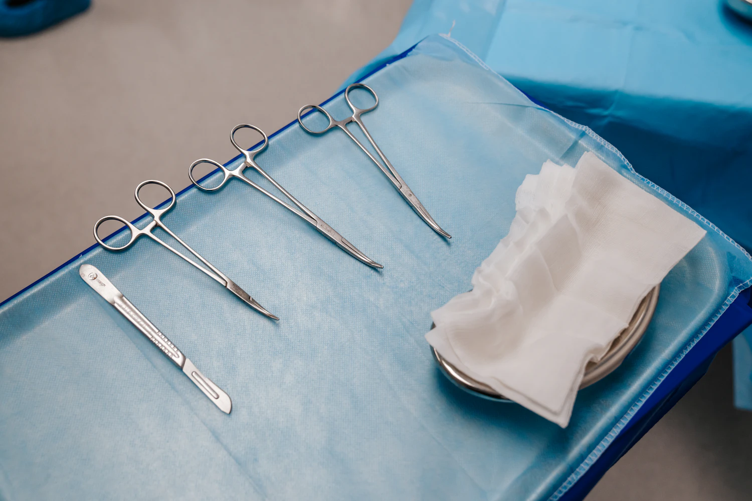 Surgical instruments laid out on a blue sterile drape