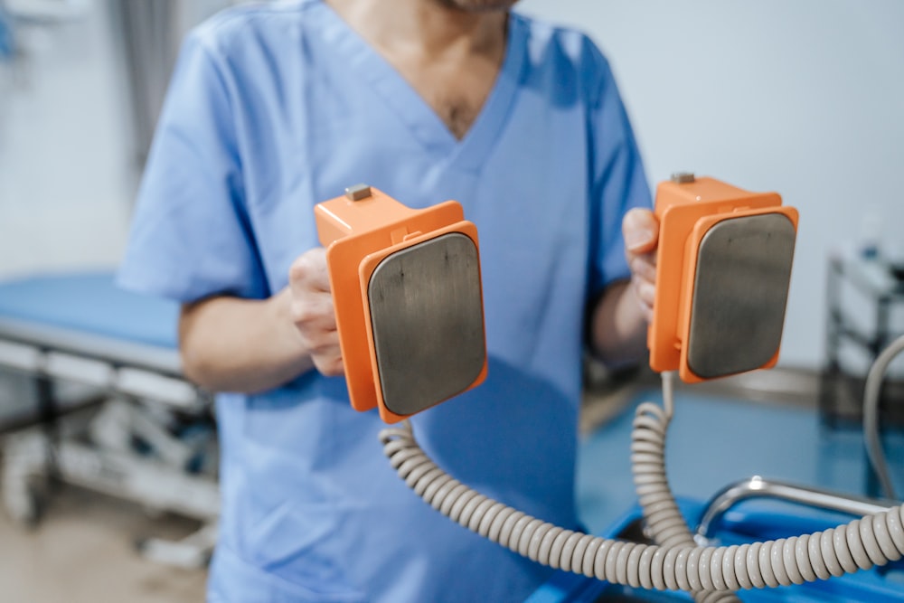 a man in scrubs is holding two orange objects