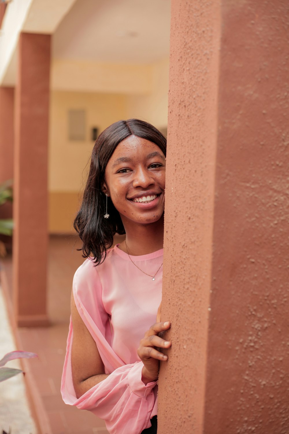 a woman is smiling and leaning against a wall