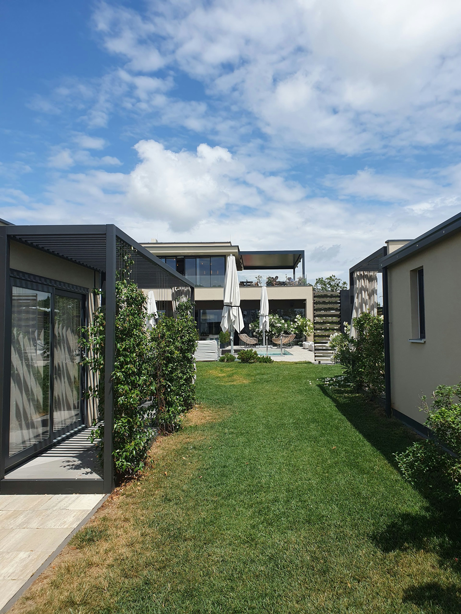 A modern, stylish home with clean lines and colorful accents nestled among greenery on a sunny day.