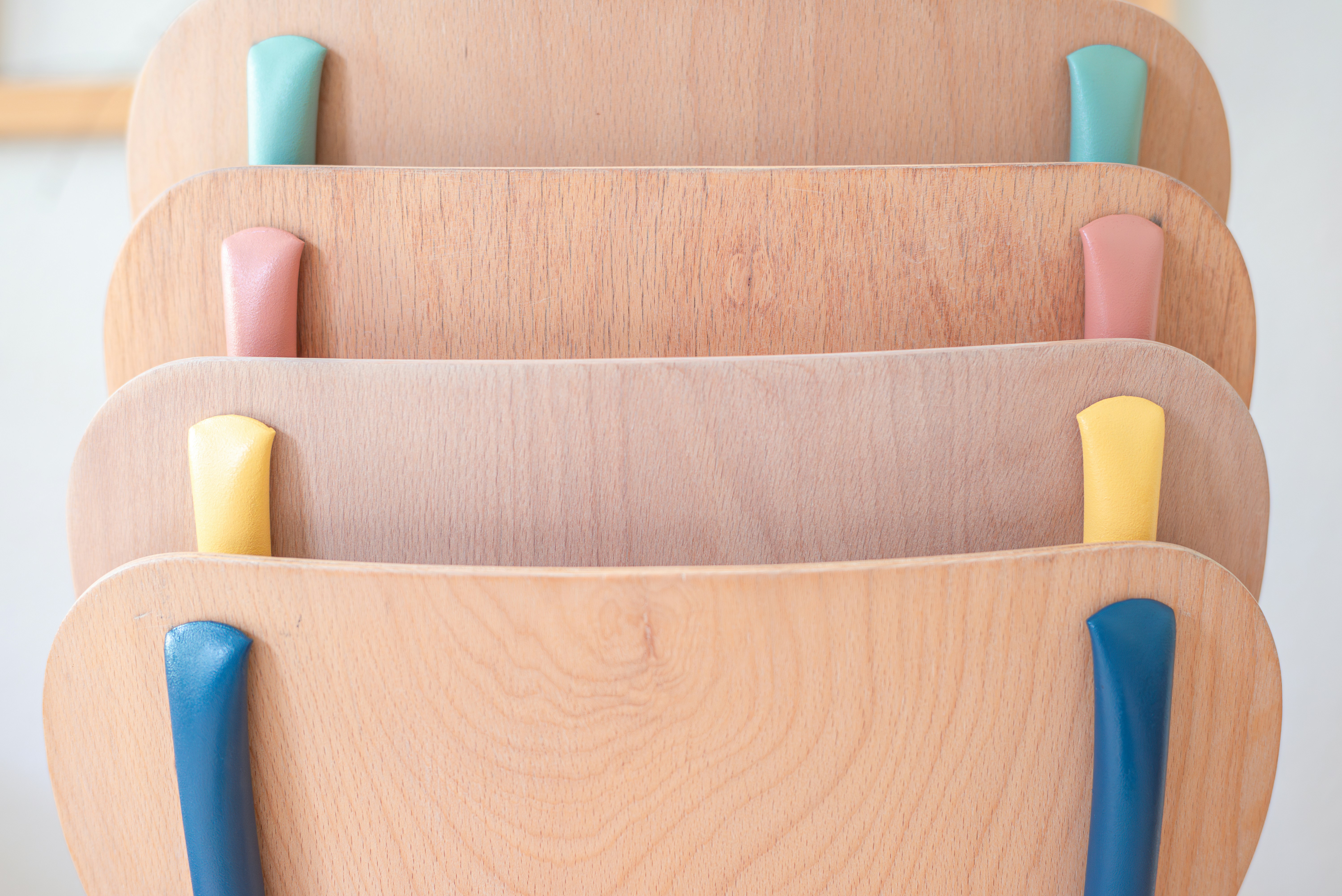 a stack of wooden chairs with blue handles