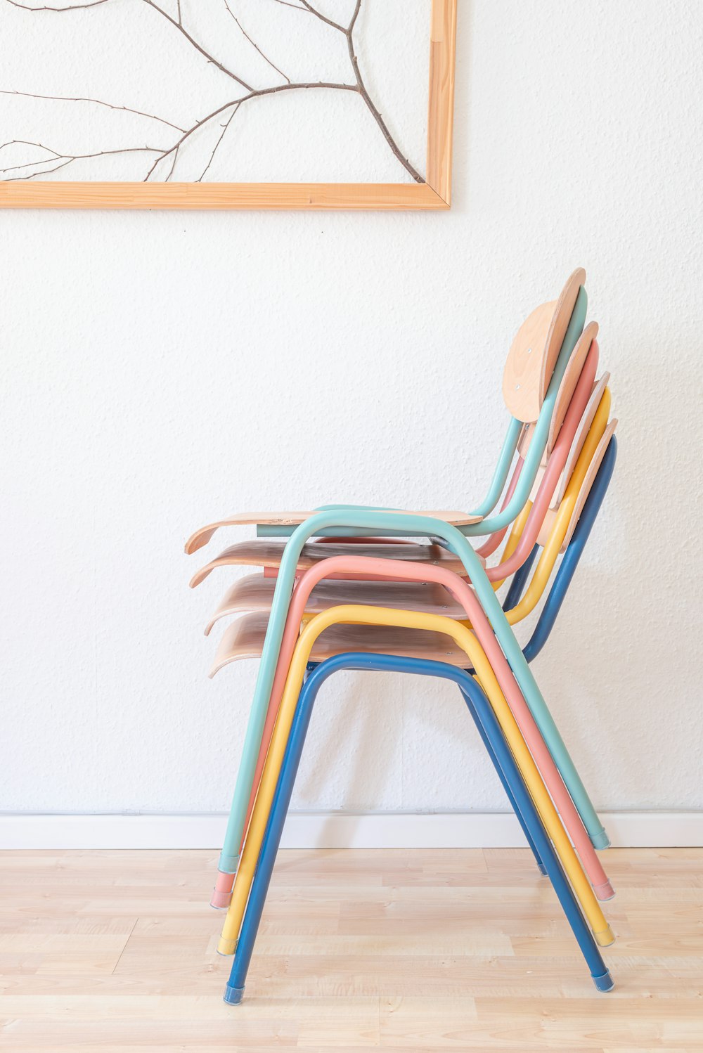 a stack of multicolored chairs against a white wall