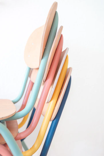 a stack of colorful wooden chairs on a white background