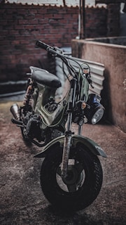 An artistic photo of a vintage motorcycle parked against a dark industrial backdrop.