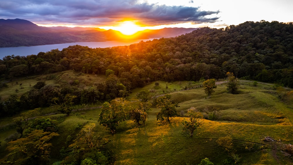 the sun is setting over a lush green valley