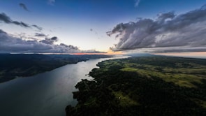 A panoramic view of Tocantins’ natural landscape with green forests and a river at sunset.