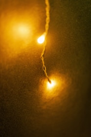 A warm and cozy ambiance created by two glowing yellow lights on a string in the foreground against a dark greenish background.