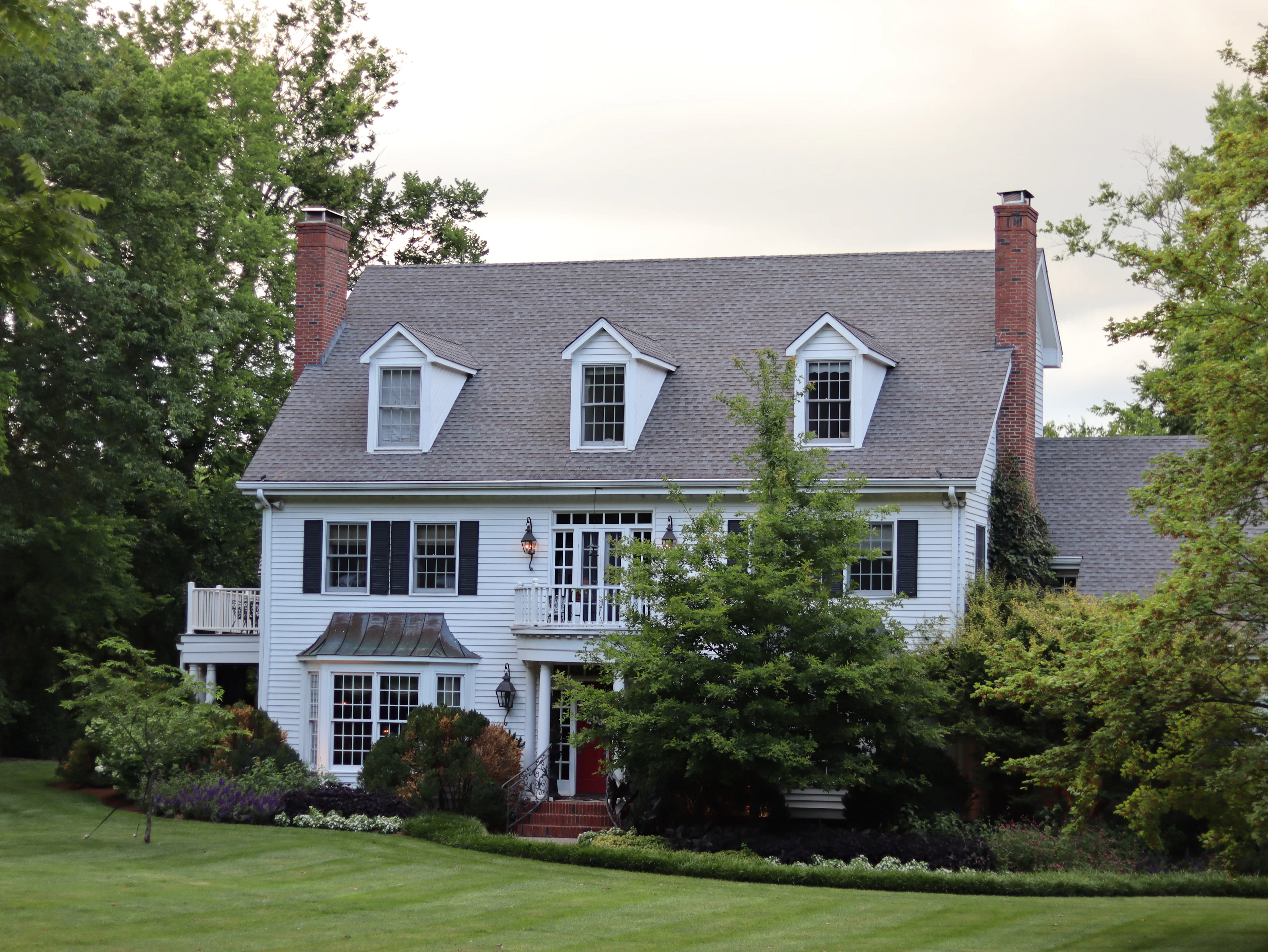 A house with shutters and windows behind a lawn