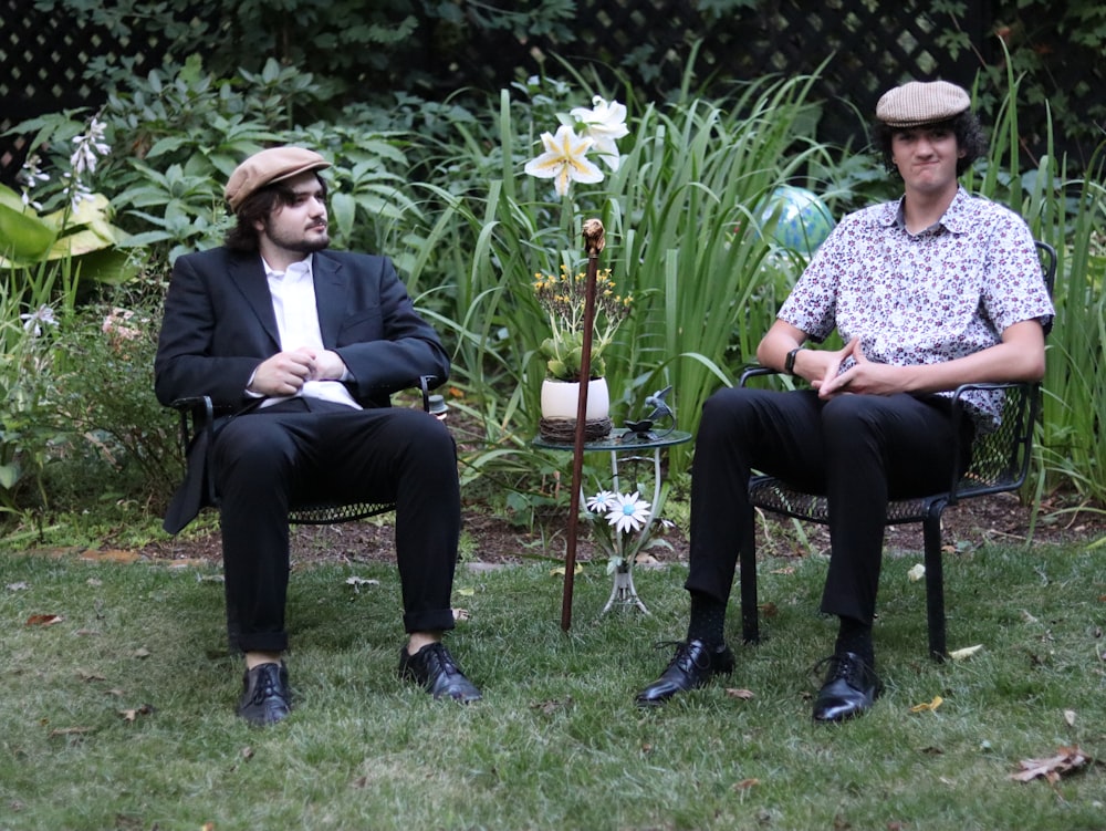 two men sitting in chairs in a yard