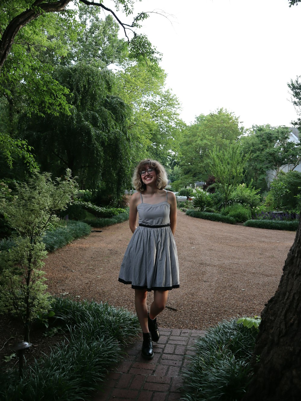 a woman in a gray dress standing on a brick walkway