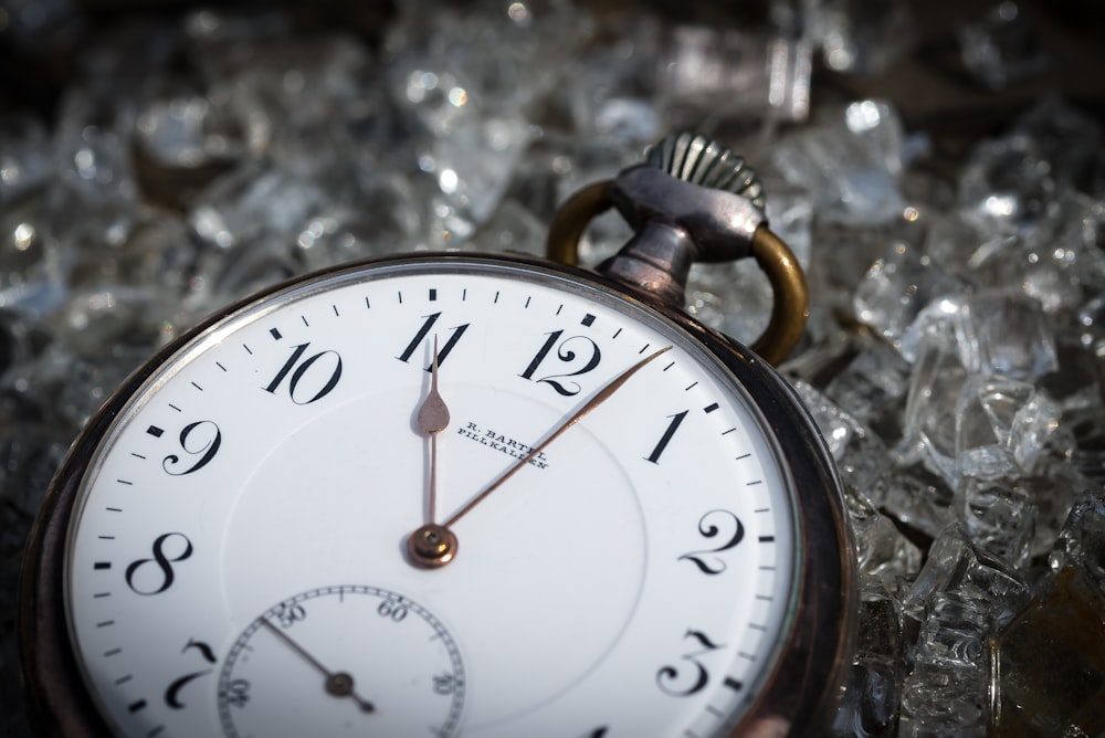 a close up of a pocket watch on a bed of ice