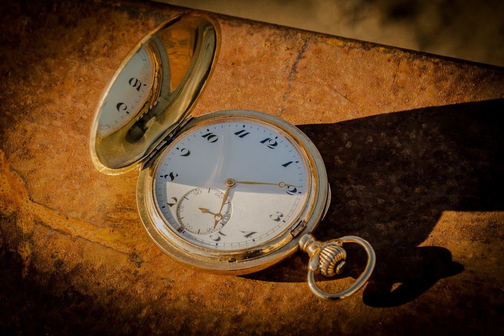 an old pocket watch laying on a rock