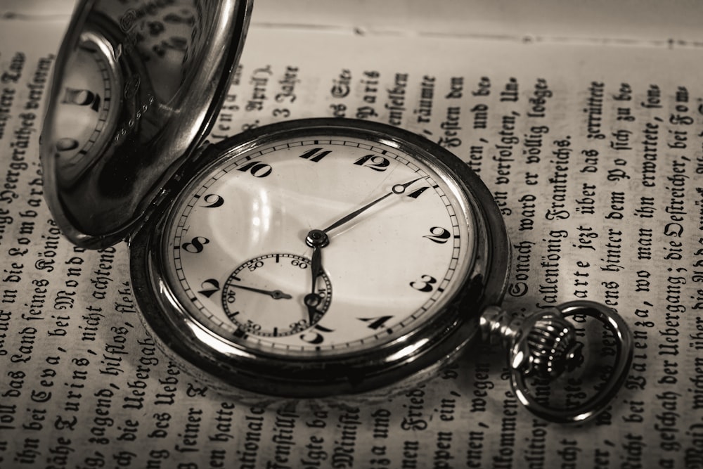 a pocket watch sitting on top of an open book