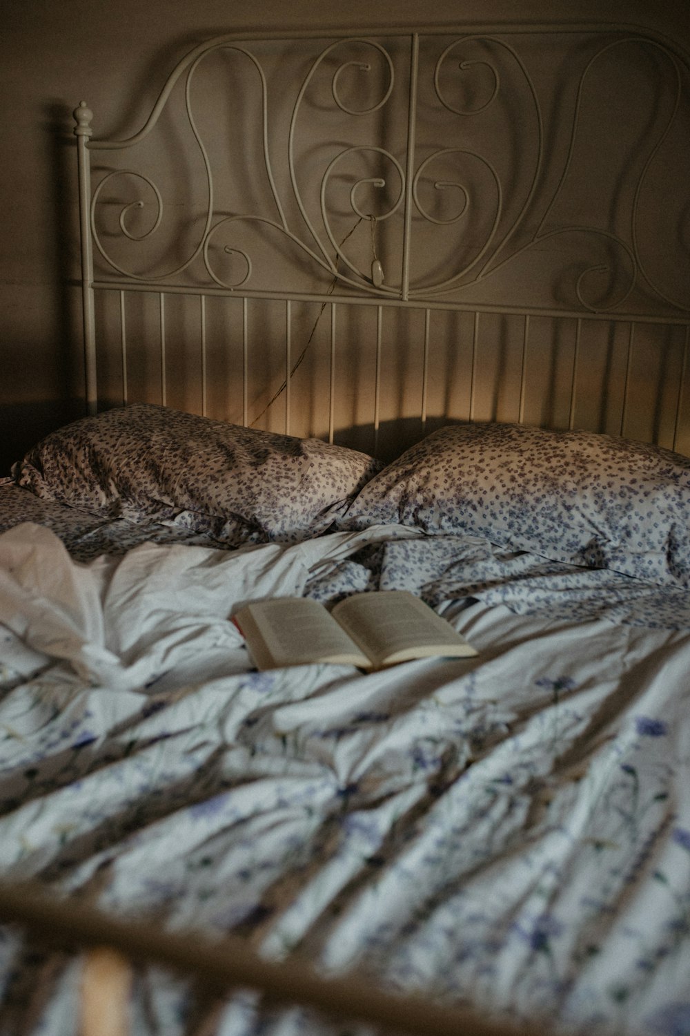 Un libro abierto está acostado en una cama desordenada